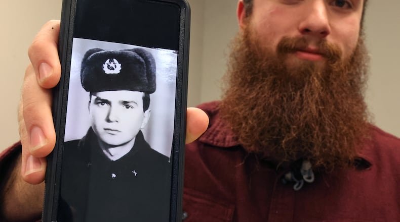 David Kravets, a music teacher at Springfeld High School, holds up a black and white picture of his Ukrainian father on his phone Wednesday, April 13, 2022. The photo was taken when his father was in the Red Army when Ukraine was part of the Soviet Union. BILL LACKEY/STAFF