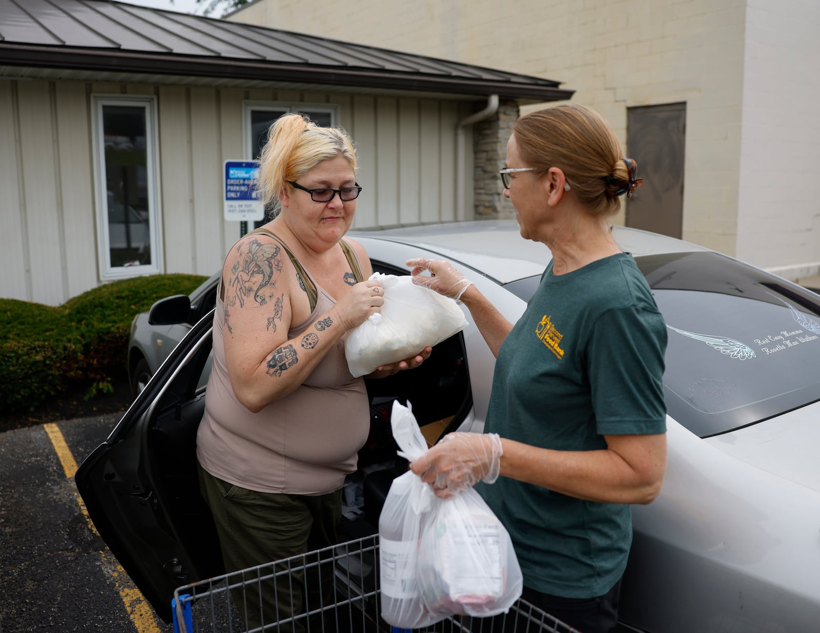 Holly Holland, left, of Springfield, receives groceries from volunteer Carol Conrad as part of OrderAhead, Second Harvest Food Bank's choice program, on Wednesday, July 9, 2025, at Second Harvest Food Bank. JOSEPH COOKE/STAFF
