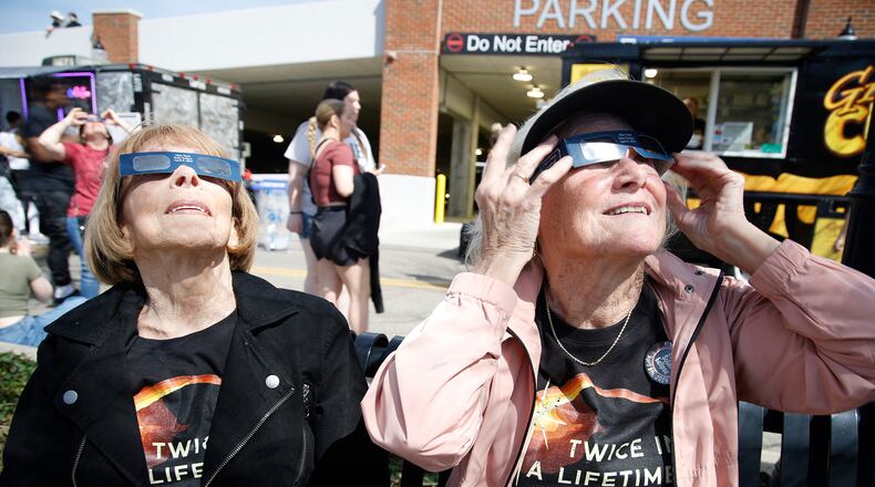 Mardi Briggs, left, and her sister, Randi Decious, both from California, watch the total eclipse Monday, April 8, 2024 at National Road Commons Park. The siblings said they were born in Springfield and hadn't been back in 70 years. BILL LACKEY/STAFF