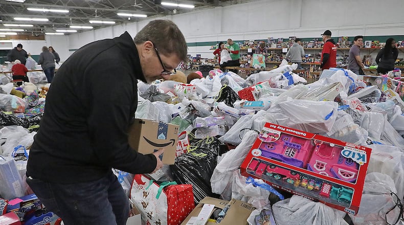 Kevin Kolenda, from Gordon Foods, sorts through the giant pile of toys dropped off by Speedway employees Friday at the Salvation Army’s “Toy Shop.” Speedway is supplying Christmas gifts for over 700 needy kids in the Springfield through the Salvation Army’s Angel Tree program. BILL LACKEY/STAFF