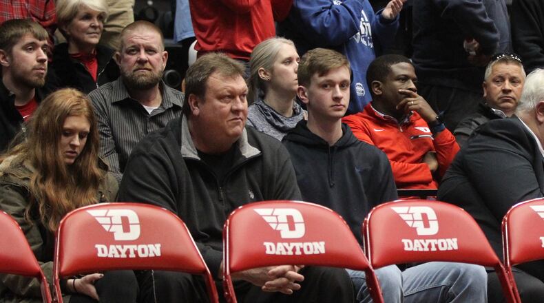 Zach Benton, center, sits behind the Dayton bench during a game against Massachusetts on Sunday, Jan. 13, 2019, at UD Arena.