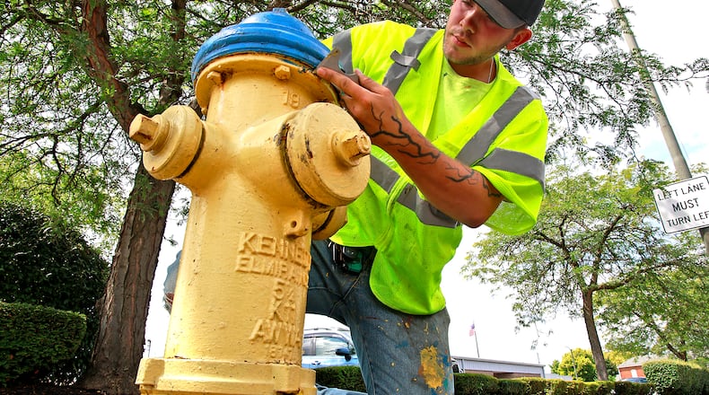 A file photo of Josh White, a city of Springfield Utilities Department seasonal employee, scraping all the loose paint off a fire hydrant along West Main Street before he paints it on July 30, 2024. BILL LACKEY/STAFF