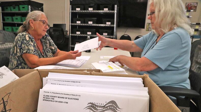 Cheryl Berry, left, and Cindy Reeder stuff absentee ballots into envelopes at the Clark County Board of Elections Monday, July 18, 2022. BILL LACKEY/STAFF