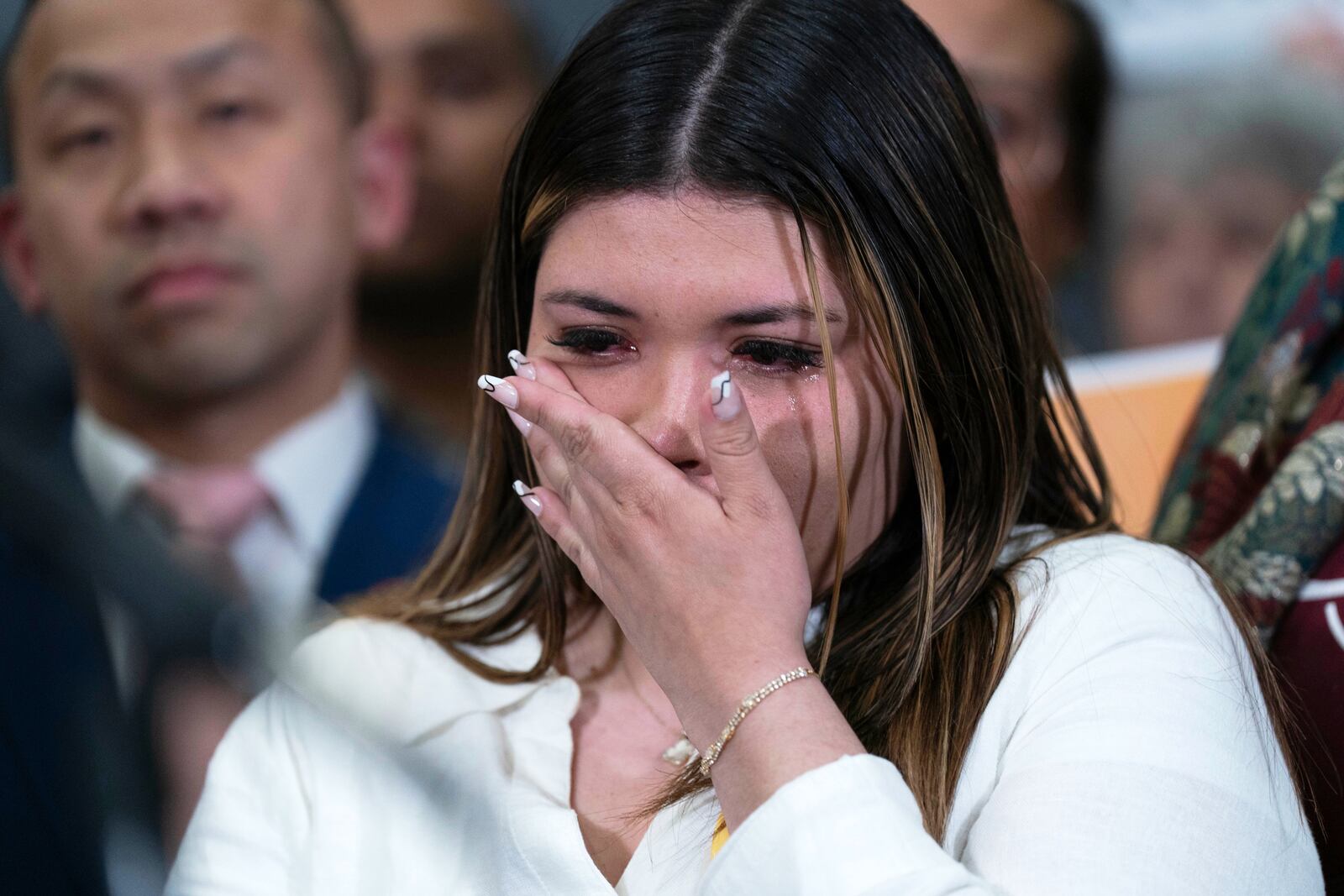 Jennifer Vasquez Sura wipes a tear from her face as Sen. Chris Van Hollen, D-Md., speaks during a news conference upon his arrival from meeting with her husband, Kilmar Abrego Garcia, in El Salvador, at Washington Dulles International Airport, in Chantilly, Va., Friday, April 18, 2025, in Washington. (AP Photo/Jose Luis Magana)