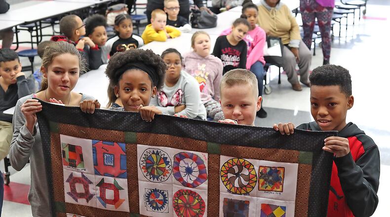 Four students in the after school program at Lincoln Elementary prepare to turn around and reveal the Freedom Quilt that the students in the program made as part of Black History Month Monday. The students each made a square for the quilt but Monday was the first time they had seen it all put together. The quilt will be on display near the office at the school. Bill Lackey/Staff