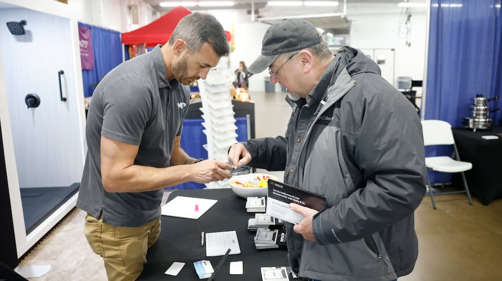 Matt Grushon, left, owner of MVP Walk-In Tub and Shower, shows Jeff Cook products he can buy from his booth during the Clark County Home and Garden Show. JOSEPH COOKE/STAFF