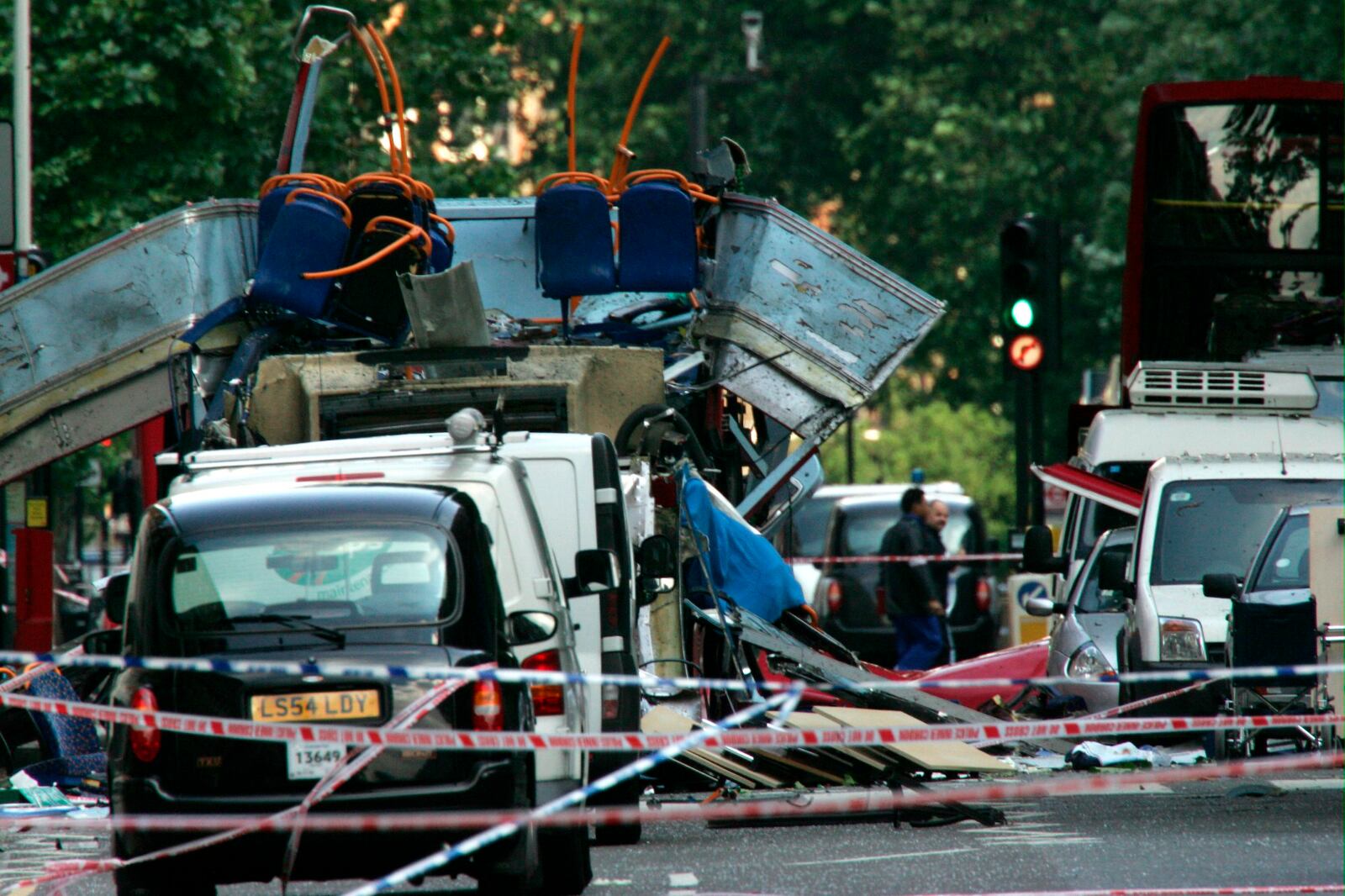 FILE - The wreckage of a double-decker bus with its top blown off by a bomb and damaged cars scattered on the road at Tavistock Square in central London, July 7, 2005. (AP Photo/Sang Tan, File)