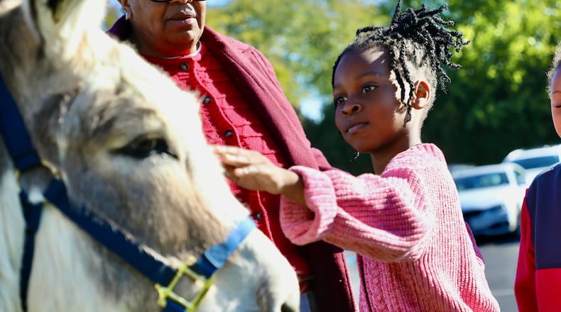 Kenwood Elementary School first grader Saelle Reguste Succes pets Biblioburro the donkey during a recent visit where the school encouraged students to read while teaching about the different ways children around the world access books. CONTRIBUTED