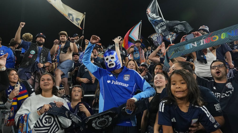 San Diego FC forward Amahl Pellegrino, center, wears a Mexican wrestling mask as he celebrates with fans after San Diego FC defeated the Portland Timbers 4-0 in Game 3 in the first round of MLS soccer's Western Conference playoffs Sunday, Nov. 9, 2025, in San Diego. (AP Photo/Gregory Bull)