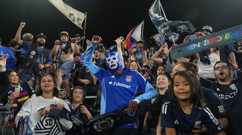 San Diego FC forward Amahl Pellegrino, center, wears a Mexican wrestling mask as he celebrates with fans after San Diego FC defeated the Portland Timbers 4-0 in Game 3 in the first round of MLS soccer's Western Conference playoffs Sunday, Nov. 9, 2025, in San Diego. (AP Photo/Gregory Bull)