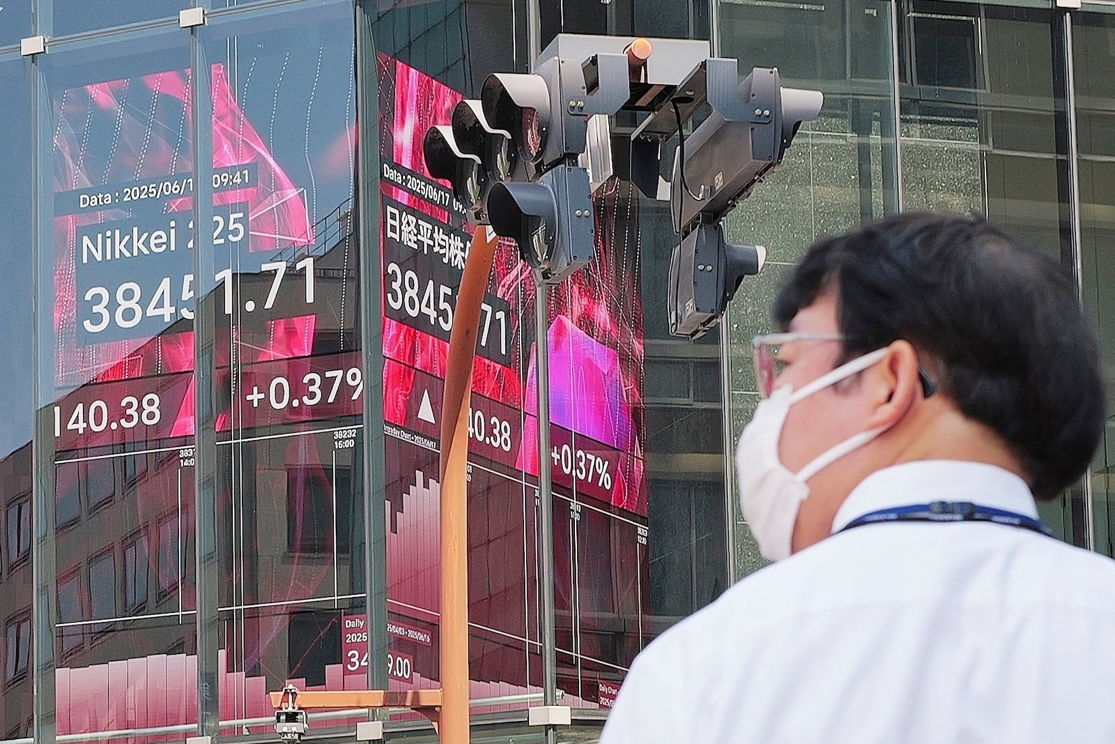 A person walks in front of an electronic stock board showing Japan's Nikkei index at a securities firm Tuesday, June 17, 2025, in Tokyo. (AP Photo/Eugene Hoshiko)