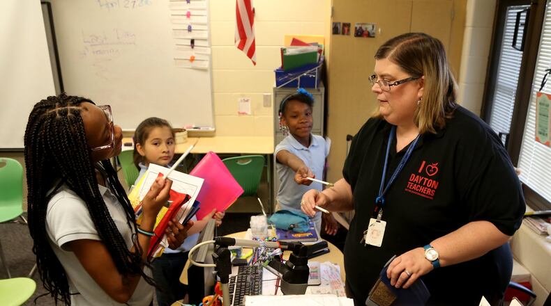 In this file photo, Melodie Larsen, then a Dayton Public Schools teacher, works with students. Teachers and nurses are among those who may be eligible for a federal loan cancelation program. LISA POWELL /STAFF