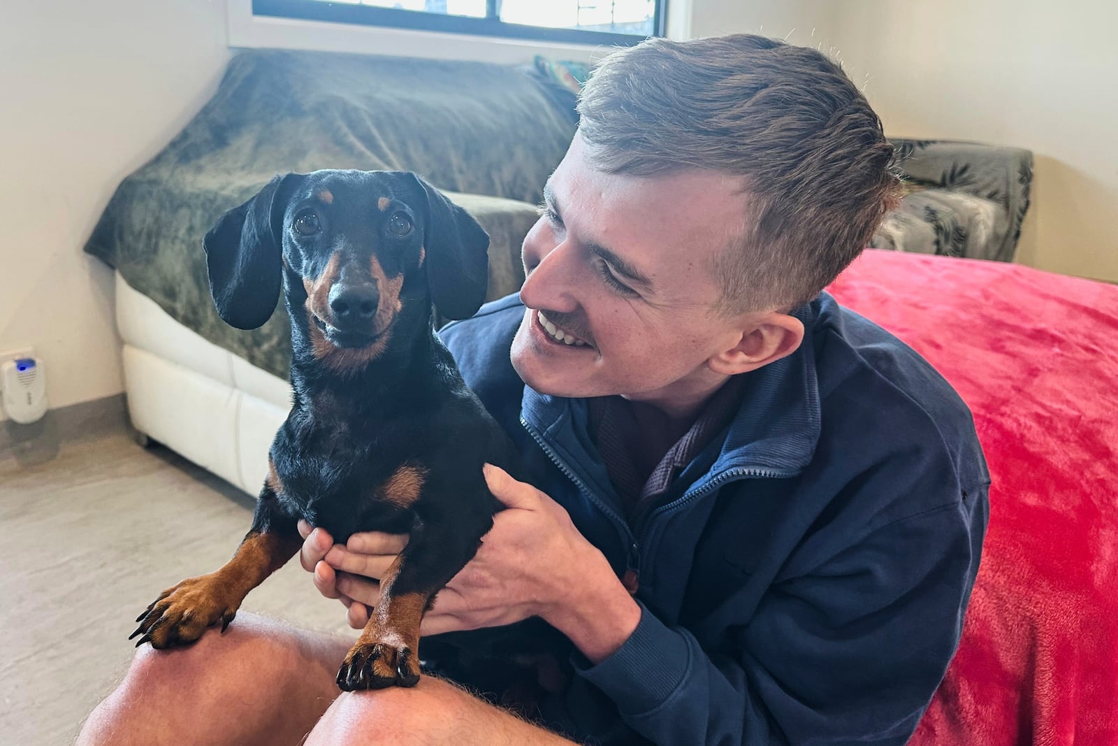 Josh Fishlock holds Valerie, his and partner Georgia Gardner's miniature dachshund after being reunited on Kangaroo Island in South Australia after Valerie was missing for 540 days, Tuesday, May 6, 2025. (Georgia Gardner via AP)