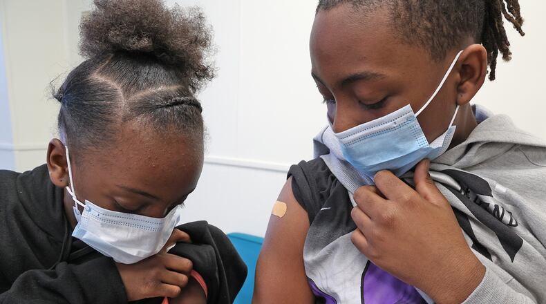 Ta'Niah Walker, 9, and her brother, Terrance, 11, check out where they got their COVID vaccine injections Friday, Feb. 25, 2022 at the Clark County Combined Health District. BILL LACKEY/STAFF