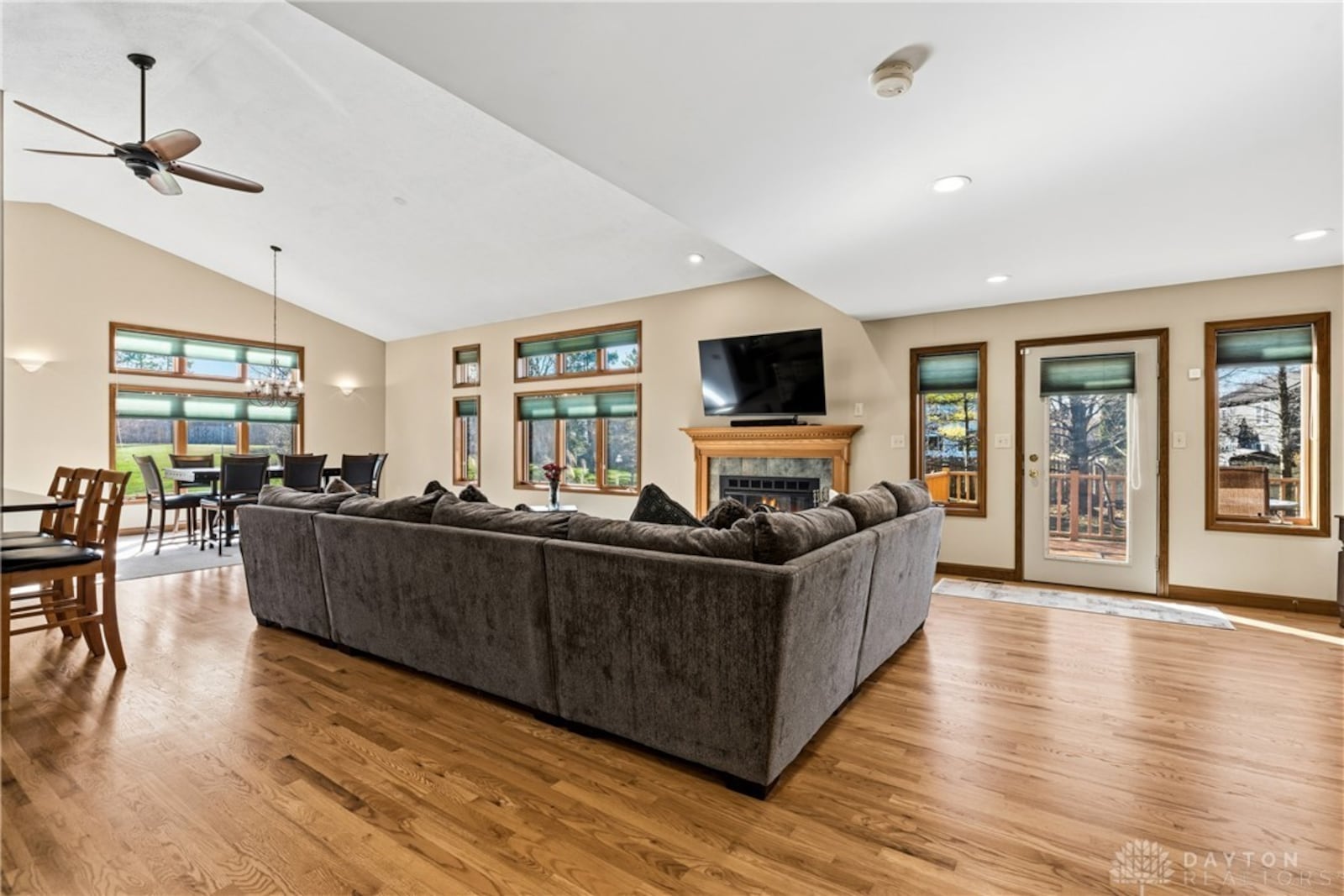 The open concept great room, dining room and kitchen in the addition has hardwood flooring and carpeting in the dining room, a vaulted ceiling and fireplace. An exterior door opens to the deck. CONTRIBUTED