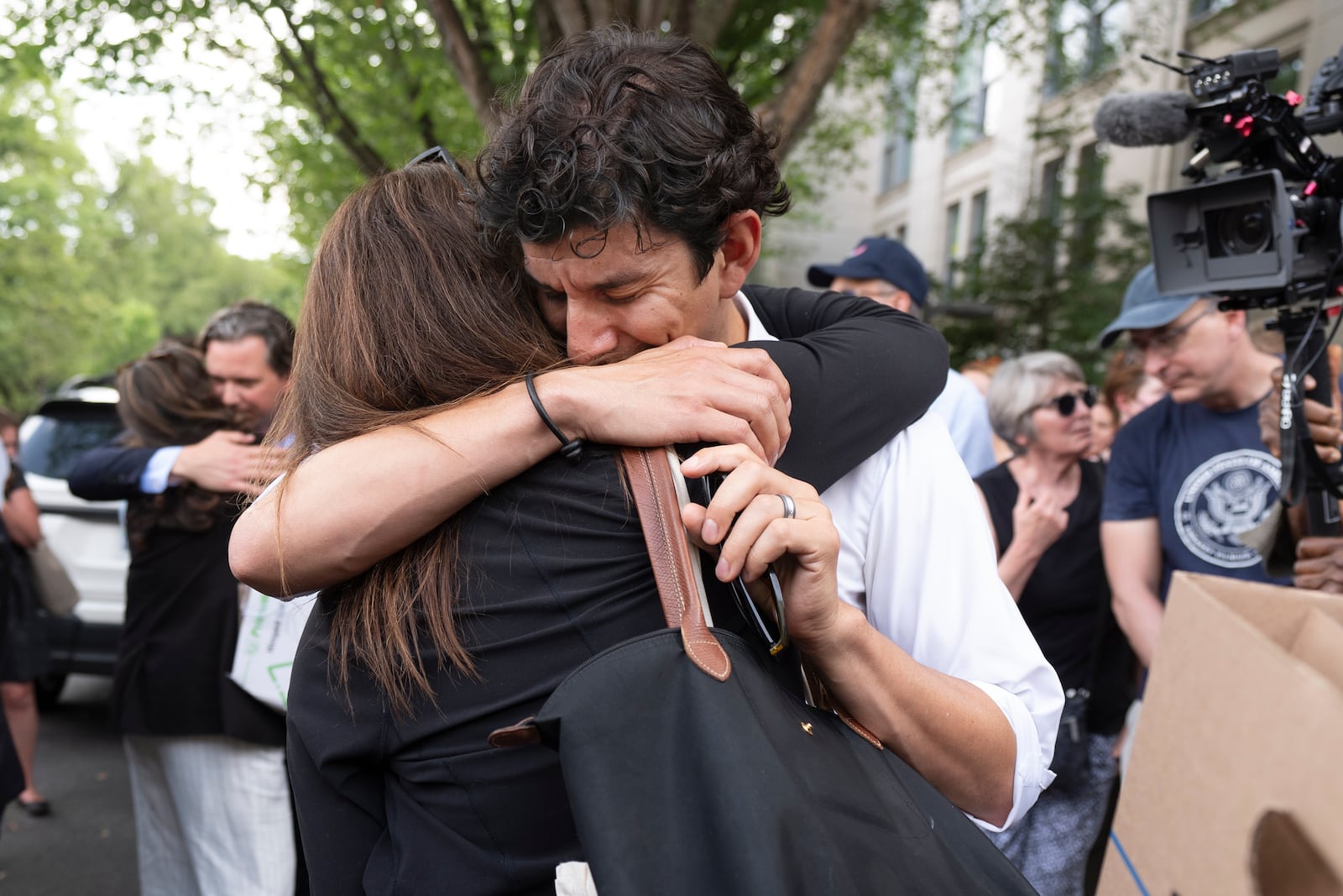 A fired State Department employee, left, is greeted outside of the Harry S. Truman Building, the headquarters of the State Department, in Washington, Friday, July 11, 2025. (AP Photo/Manuel Balce Ceneta)