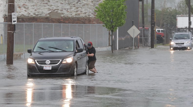 A stranger helps a man by pushing him out of the high water on North Street in Springfield. BILL LACKEY/STAFF
