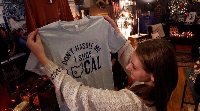 Malory Janicki looks at a shirt promoting shopping locally Tuesday, Nov. 22, 2022 at Champion City Guide and Supply in downtown Springfield. BILL LACKEY/STAFF