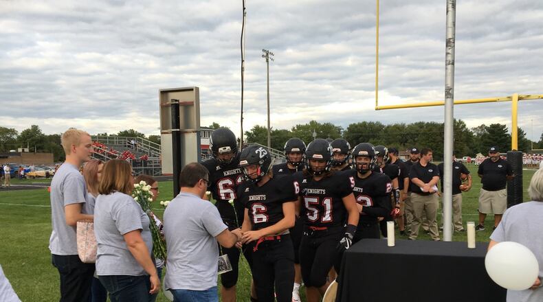 Greenon High School football players offer flowers to the family of former teammate Connor Williams, who died following a car crash with soccer player David Waag on Aug. 20, prior to the Knights’ home football opener on Friday. Brett Turner/CONTRIBUTED