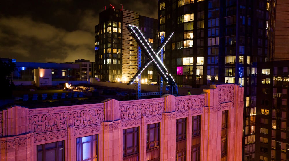 FILE - Workers install lights on an "X" sign atop the company headquarters in downtown San Francisco on July 28, 2023. (AP Photo/Noah Berger, File)