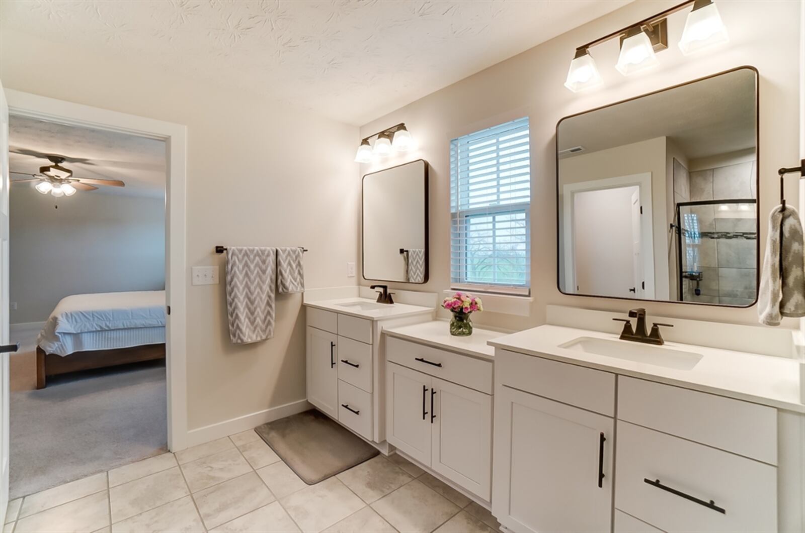 The bath has two elevated vanities with single sinks and a storage cabinet. 