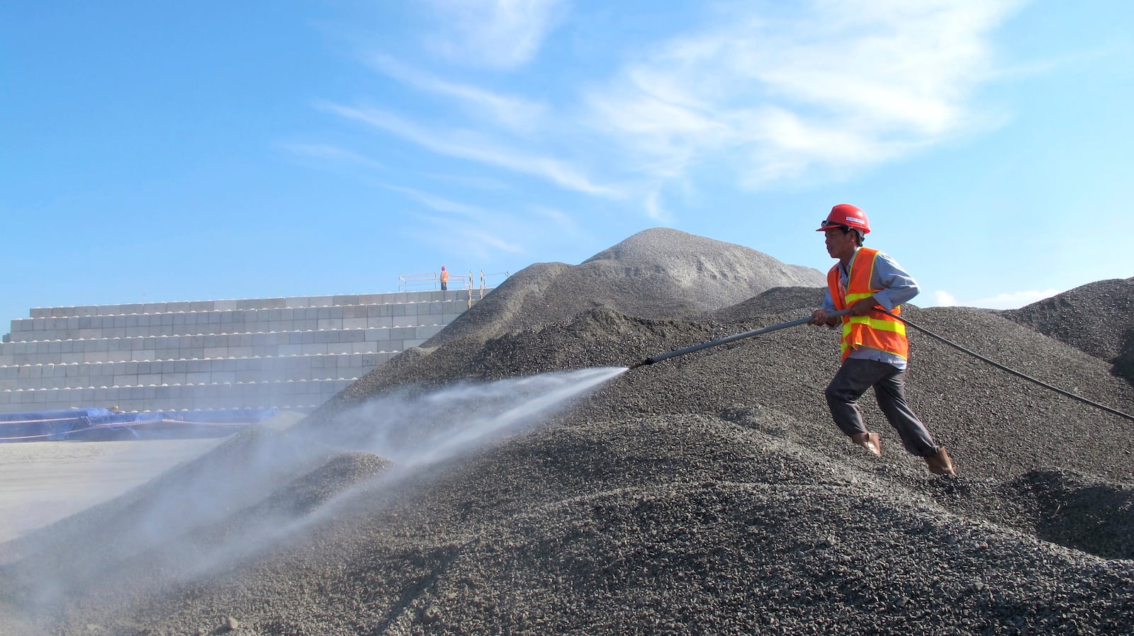 FILE- A Vietnamese worker sprays water over stones to be used in the construction of a silo for storing soil contaminated with Agent Orange dioxide at the site of a former American airbase in Danang, Vietnam on Wednesday, April 24, 2013. (AP Photo/Hau Dinh, File)