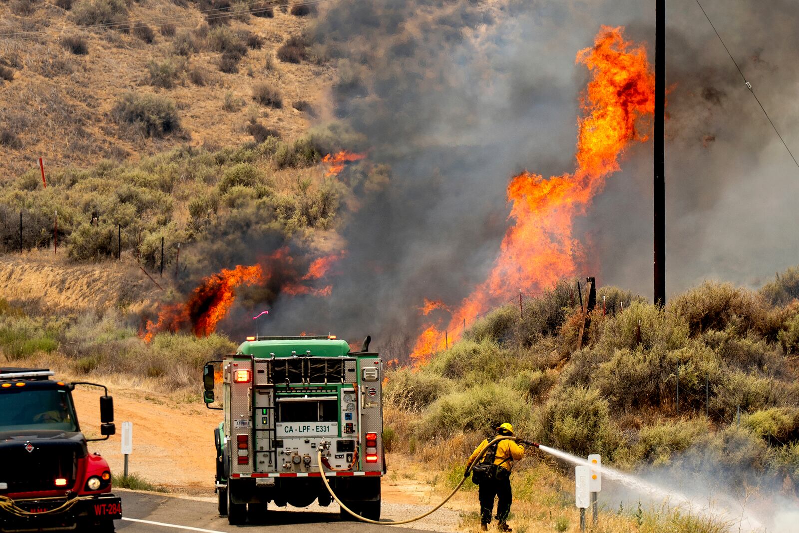 A firefighter battles the Madre Fire as it makes a run along Highway 166, Thursday, July 3, 2025, in San Luis Obispo County, Calif. (AP Photo/Noah Berger)