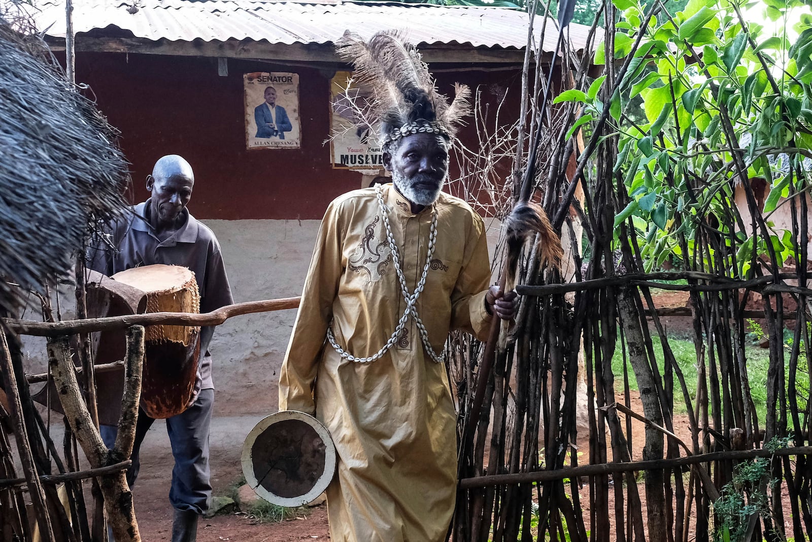 Seer Atukung Tafala, front, walks inside his igloo-like shrine in Kampala, Uganda Saturday, June 21, 2025. (AP Photo/Hajarah Nalwadda)
