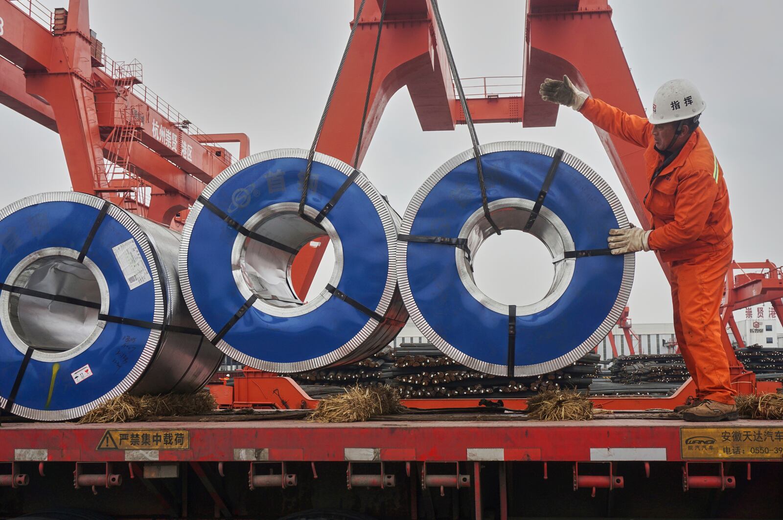 A worker loads rolls of steel plate at a steel market in Hangzhou in east China's Zhejiang province, Monday, March 31, 2025. (Chinatopix Via AP)