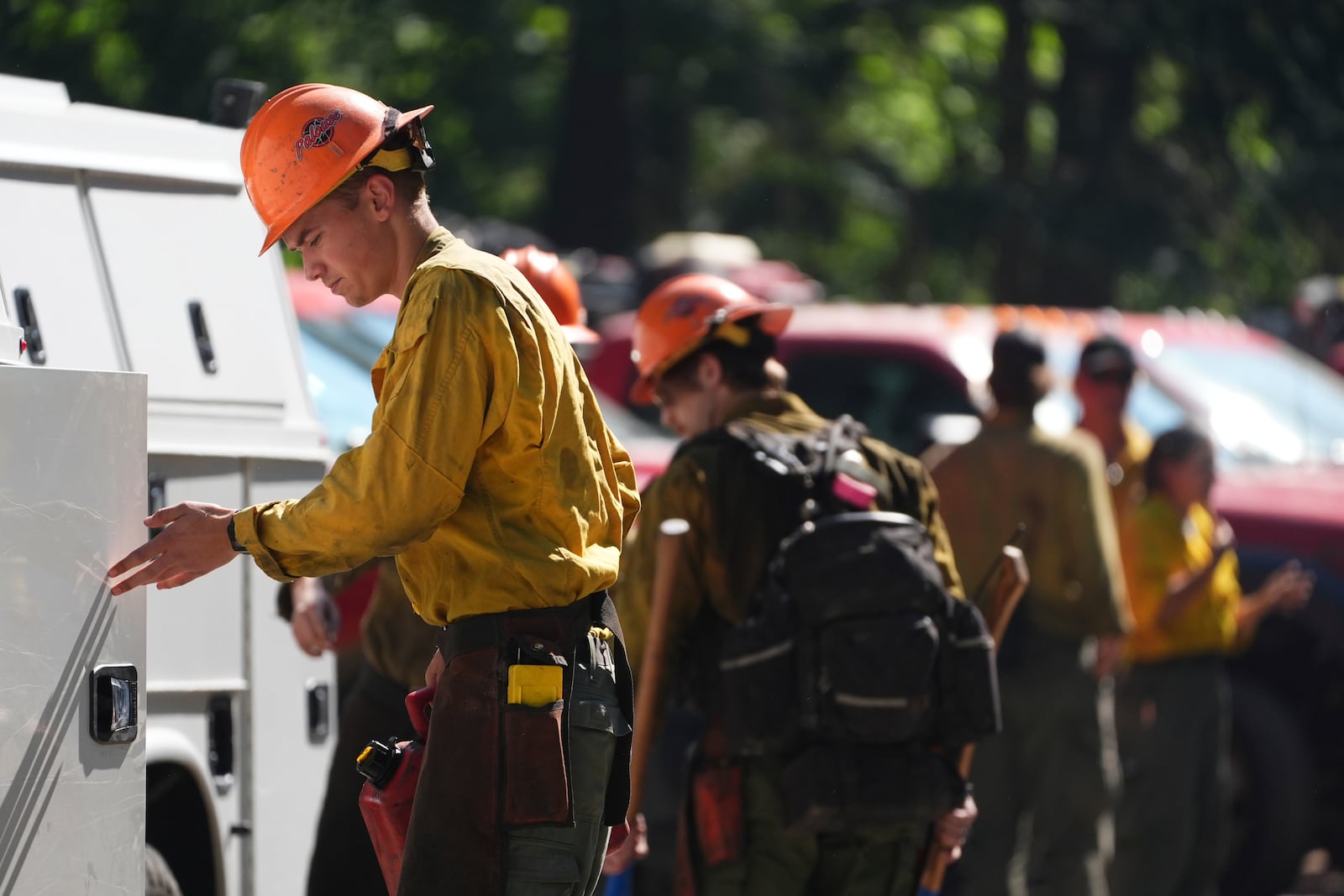 A firefighter with the United States Forest Service prepares gear at a staging area near the scene the day after a shooter ambushed and killed multiple firefighters responding to a wildfire at Canfield Mountain Monday, June 30, 2025, in Coeur D'Alene, Idaho. (AP Photo/Lindsey Wasson)