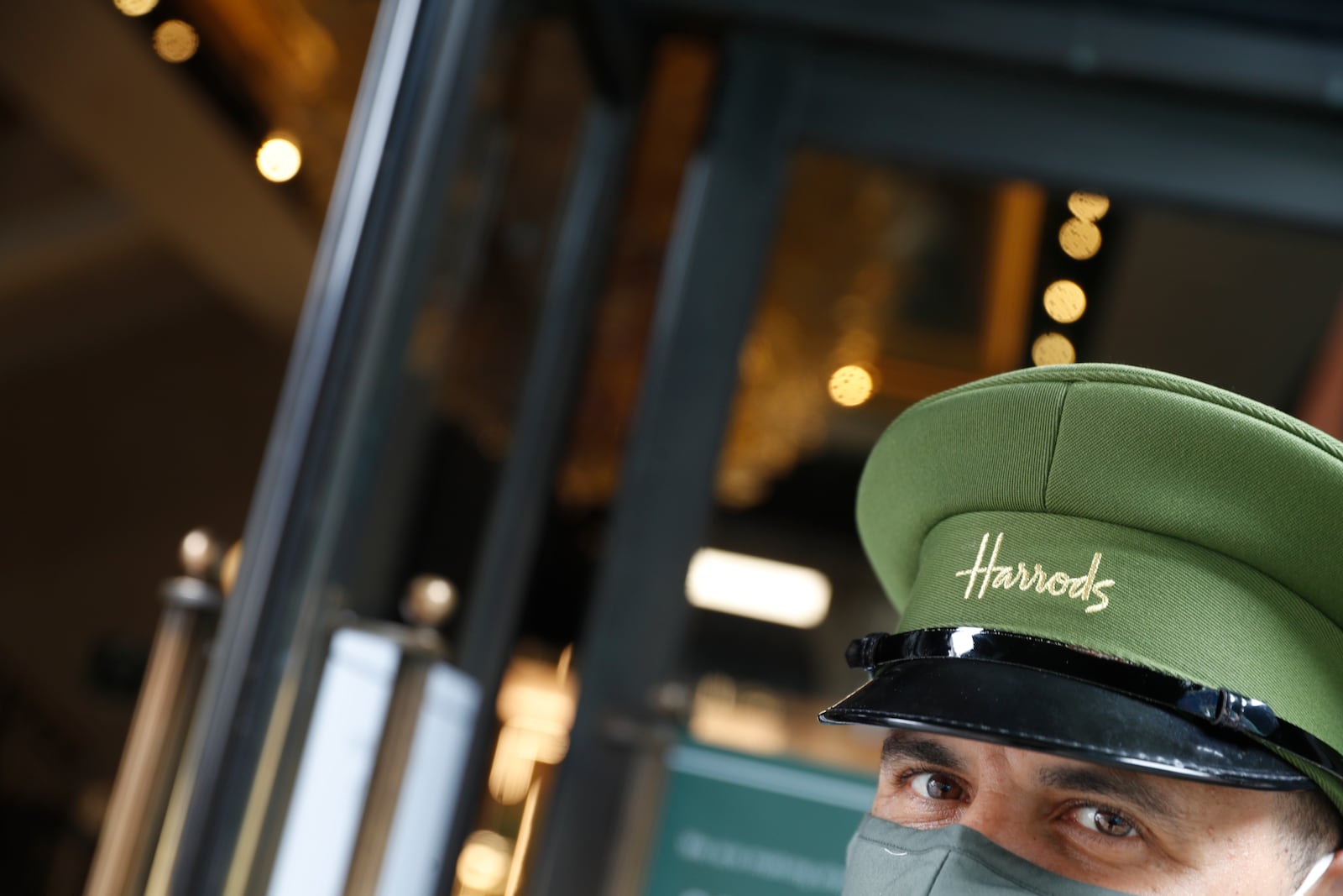 FILE - A doorman wearing a mask outside Harrods department store opens the door for customers in London, Wednesday, July 1, 2020. (AP Photo/Alastair Grant, file)