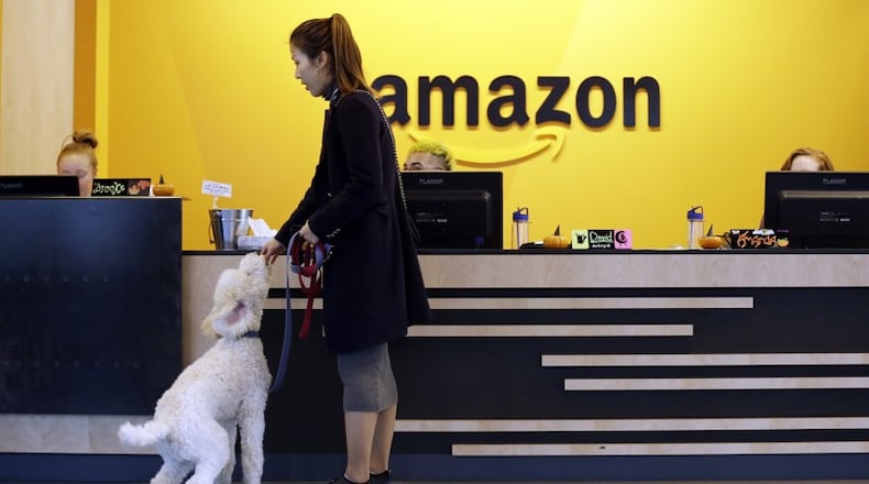 In this Wednesday, Oct. 11, 2017, photo, an Amazon employee gives her dog a biscuit as the pair head into a company building, where dogs are welcome, in Seattle. Amazon says it received 238 proposals from cities and regions hoping to be the home of the company’s second headquarters. The online retailer kicked off its hunt for a second headquarters in September, promising to bring 50,000 new jobs. It will announce a decision sometime in 2018. (AP Photo/Elaine Thompson, File)