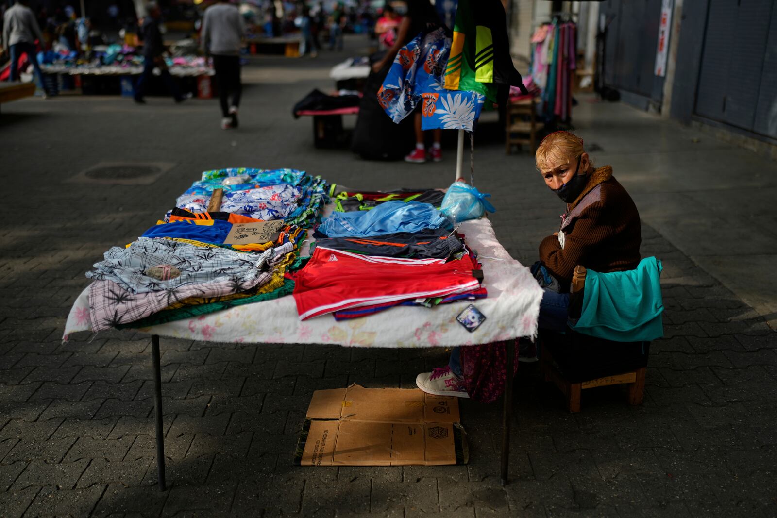 A clothing vender sits at her table on the sidewalk in Caracas, Venezuela, Friday, April 11, 2025. (AP Photo/Ariana Cubillos)