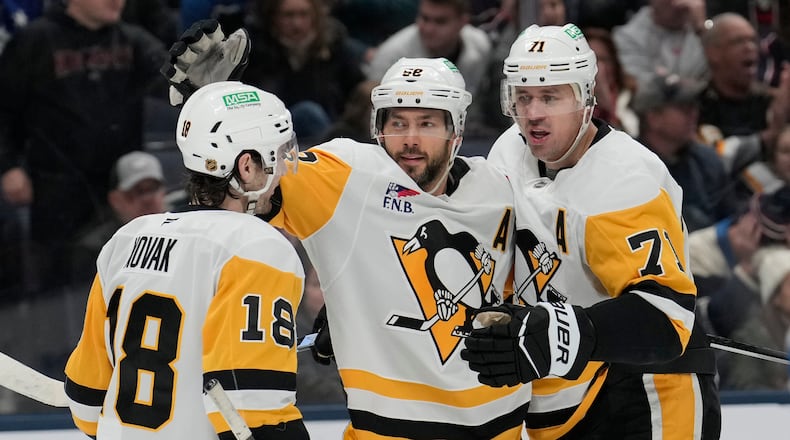 Pittsburgh Penguins center Tommy Novak (18), defenseman Kris Letang (58) and center Evgeni Malkin (71) celebrate Letang's overtime goal during an NHL hockey game against the Columbus Blue Jackets, Friday, Nov. 28, 2025, in Columbus, Ohio. (AP Photo/Carolyn Kaster)