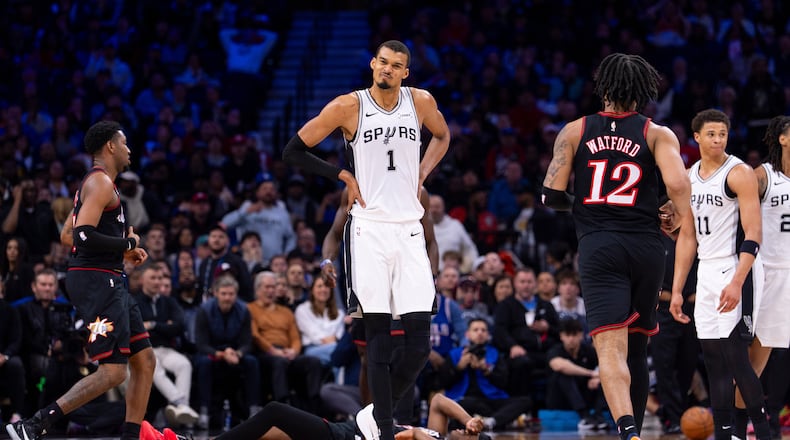San Antonio Spurs' Victor Wembanyama, center, reacts to the foul by Carter Bryant, right, on Philadelphia 76ers' VJ Edgecombe, center floor, during the first half of an NBA basketball game, Tuesday, March 3, 2026, in Philadelphia. (AP Photo/Chris Szagola)