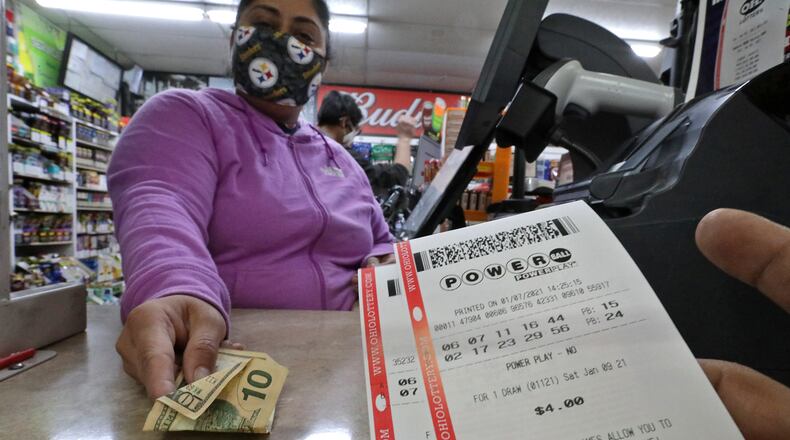 A customer purchases Mega Million and Powerball tickets from Hiral Patel at the Plum Food Mart in Springfield. BILL LACKEY/STAFF