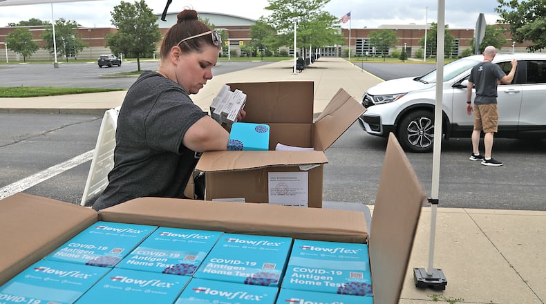 Stephanie Johnson and Chris Cook, from the Clark County Combined Health District, pass out COVID-19 home test kits in a drive-thru in June in the parking lot at Springfield High School. BILL LACKEY/STAFF