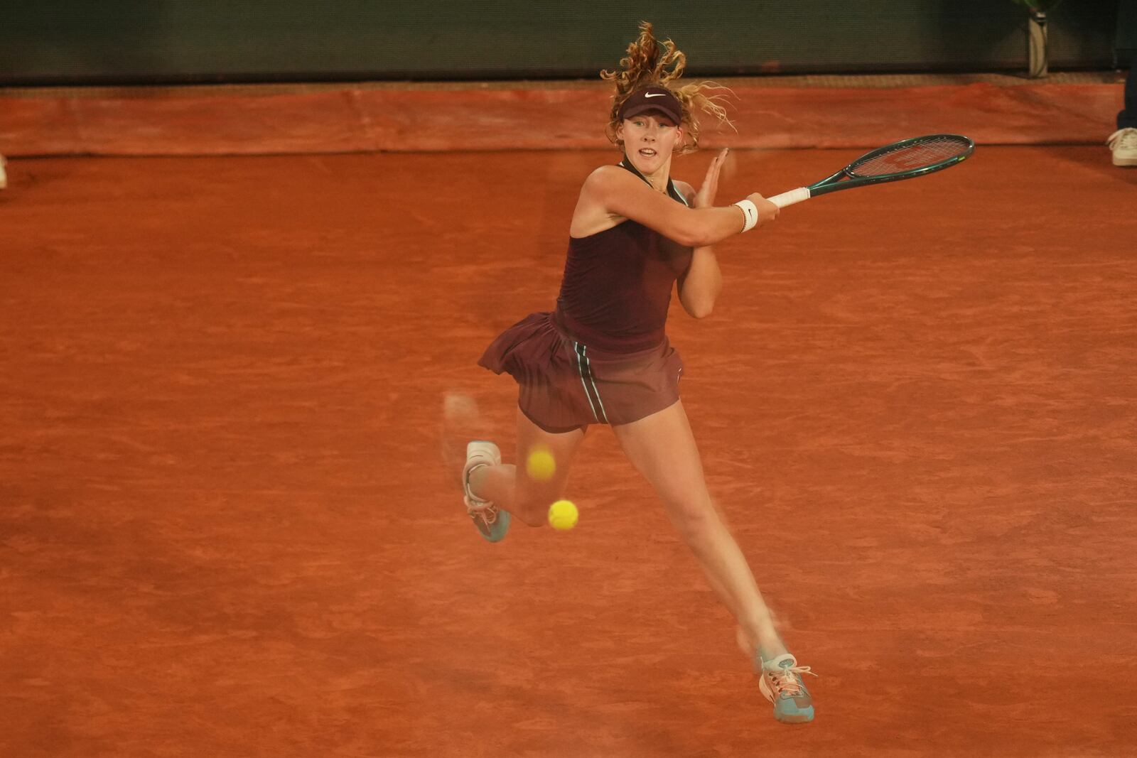 Russia's Mirra Andreeva is reflected in a glass as she serves against France's Lois Boisson during their quarterfinal match of the French Tennis Open at the Roland-Garros stadium in Paris, Wednesday, June 4, 2025. (AP Photo/Aurelien Morissard)