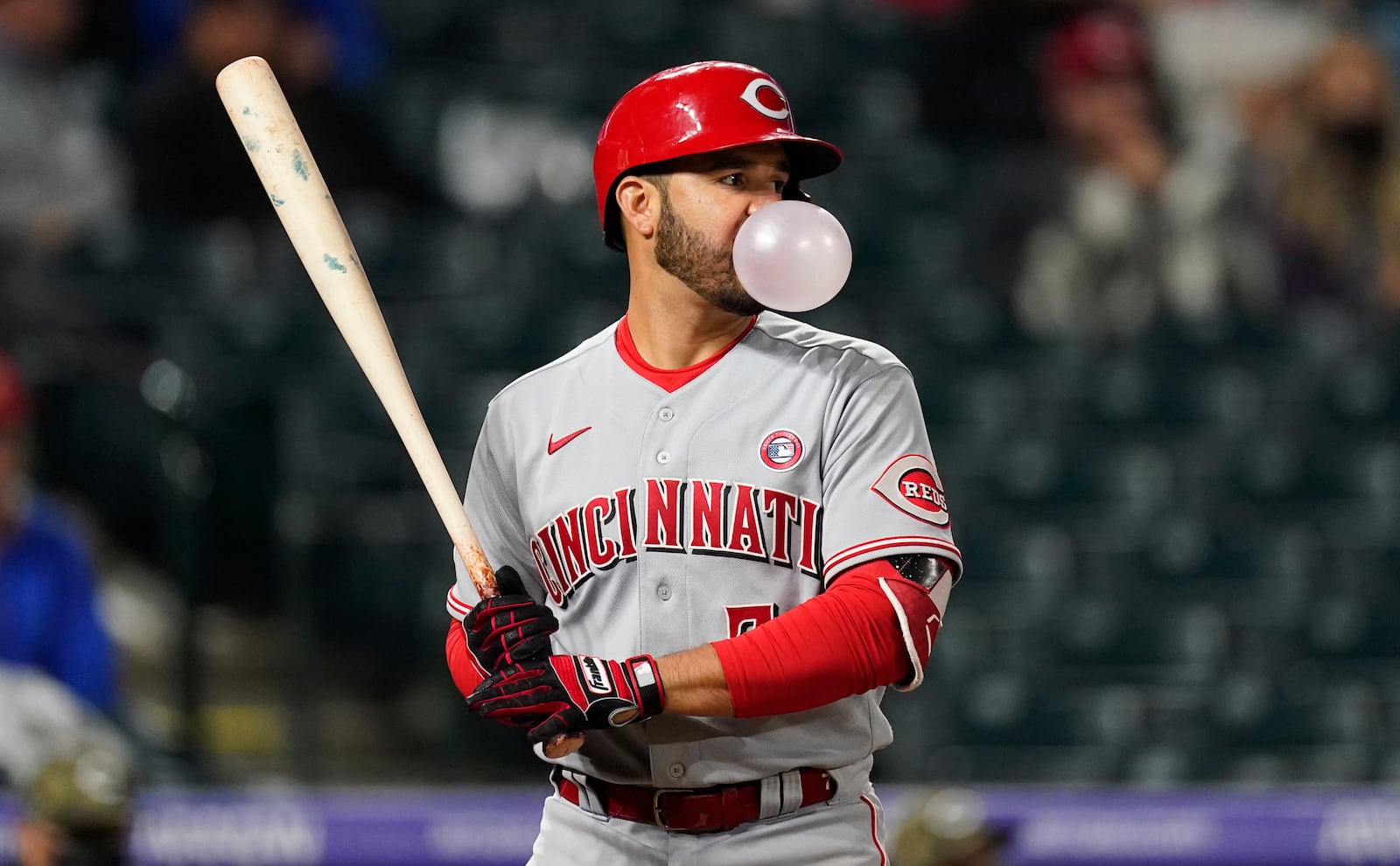 Cincinnati Reds' Eugenio Suarez blows a bubble as he waits for a pitch from Colorado Rockies' Jordan Sheffield during the 10th inning of a baseball game Saturday, May 15, 2021, in Denver. (AP Photo/David Zalubowski)