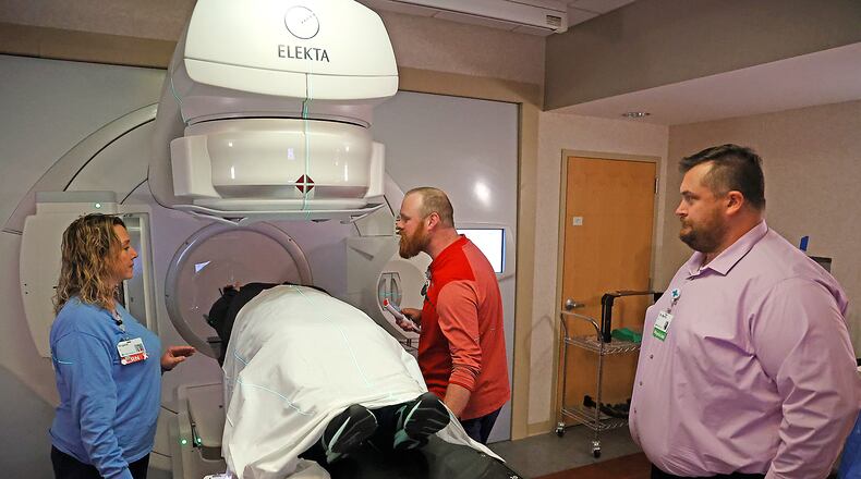 Wes England, center, gets a woman set up in the Linear Accelerator as Anglea Wagner, lung cancer coordinator, and Dr. Joshua Martin talk to her Friday, Nov. 18, 2022 at the Springfield Cancer Center. BILL LACKEY/STAFF