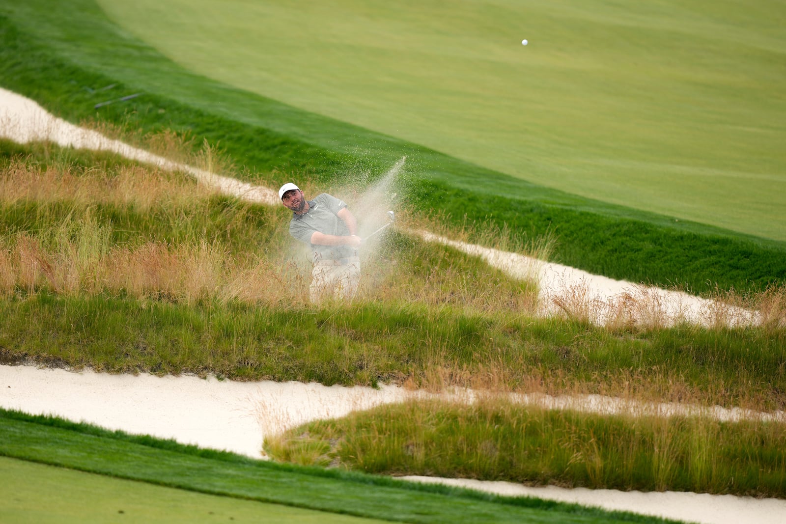 Scottie Scheffler plays out of the Church Pews bunker on the third hole during the second round of the U.S. Open golf tournament at Oakmont Country Club Friday, June 13, 2025, in Oakmont, Pa. (AP Photo/Charlie Riedel)