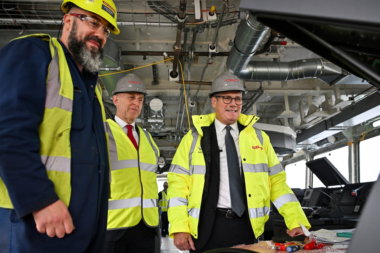 Britain's Prime Minister Keir Starmer, right, and Britain's Defence Secretary John Healey, center, speak to a member of staff during a visit to the BAE Systems'Govan facility, in Glasgow, Scotland, Monday June 2, 2025. (Andy Buchanan, Pool Photo via AP)
