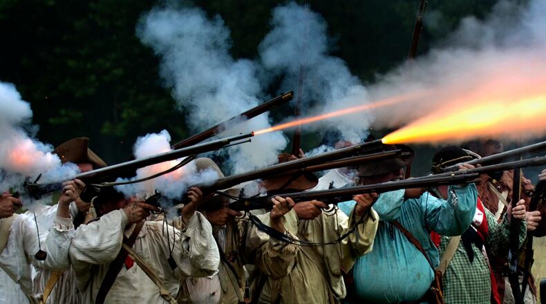 Fire explodes from a row of militia muskets as the militiamen in the 225th anniversary re-enactment of the Battle of Peckuwe take aim at the Native American warriors Sunday, July 17, 2005, at George Rogers Clark Park in Springfield. The re-enactment commemorates the largest Revolutionary War battle fought west of the Allegheny Mountains which took place on the site of the current state park. Staff photo by Bill Lackey