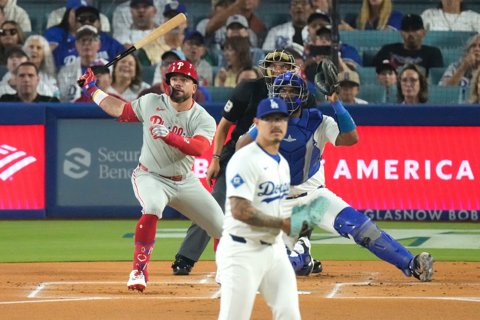 Philadelphia Phillies' Kyle Schwarber, left, hits a solo home run as Los Angeles Dodgers starting pitcher Anthony Banda, second from left, and catcher Chuckie Robinson watch during the first inning of a baseball game Monday, Sept. 15, 2025, in Los Angeles. (AP Photo/Mark J. Terrill)