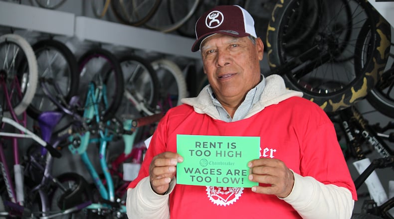 Ismael Cortes Estrada poses for a photo holding one of the signs advocates used in the campaign for updating the city's minimum wage law, in Santa Fe, New Mexico, on Wednesday, Nov. 26, 2025. (AP Photo/Susan Montoya Bryan)