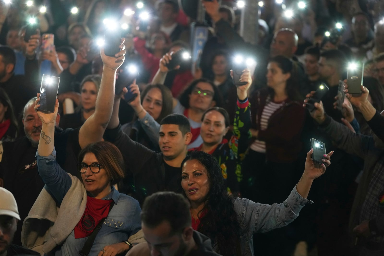 Turkish Cypriot protesters hold the lighted mobile phones aloft as they gather to protest against what they say is Turkey's attempt to erode their secular roots and to strengthen the hold of political Islam over their society, in the northern half of ethnically divided Cyprus' capital Nicosia, on Friday, May 2, 2025. (AP Photo/Petros Karadjias)