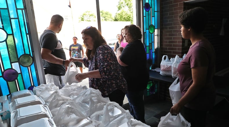 Kelly Myers, center, a H.O.P.E. volunteer, passes out free meals with other volunteers Wednesday. H.O.P.E, a nonprofit organization in Springfield, has served over 15,000 meals since the beginning of the coronavirus pandemic. BILL LACKEY/STAFF