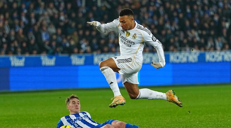 Real Madrid's Kylian Mbappe, top, challenges for the ball during the Spanish La Liga soccer match between Alaves and Real Madrid in Vitoria-Gasteiz, Spain, Sunday, Dec. 14, 2025. (AP Photo/Miguel Oses)