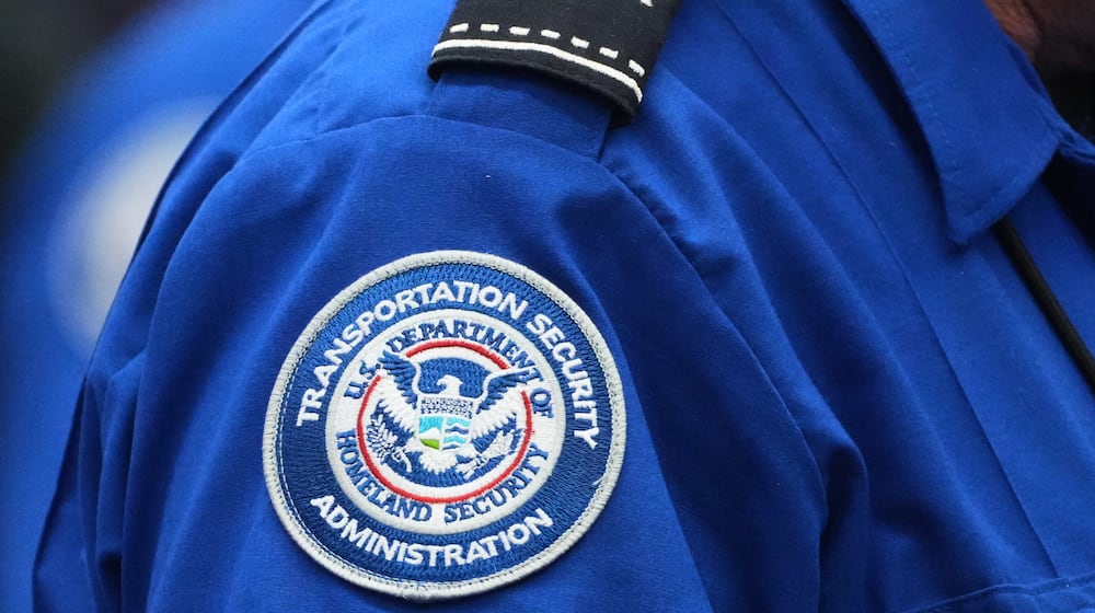 A TSA agent wears a Transportation Security Administration badge while checking identification at Seattle-Tacoma International Airport, Thursday, Nov. 6, 2025, in SeaTac, Wash. (AP Photo/Lindsey Wasson)