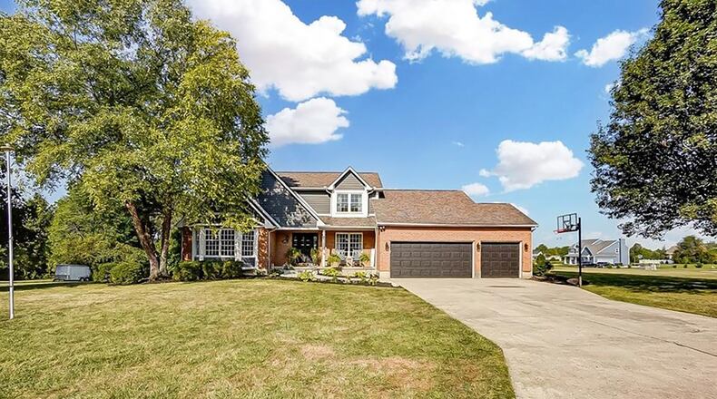The brick and vinyl two story has a covered front porch and attached three car garage.